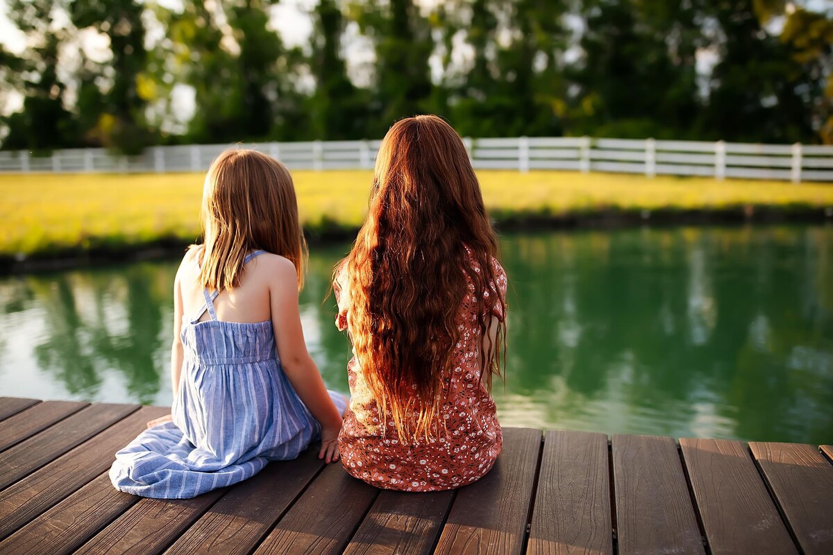 Two girls sitting on the dock at the Parkton Place pond