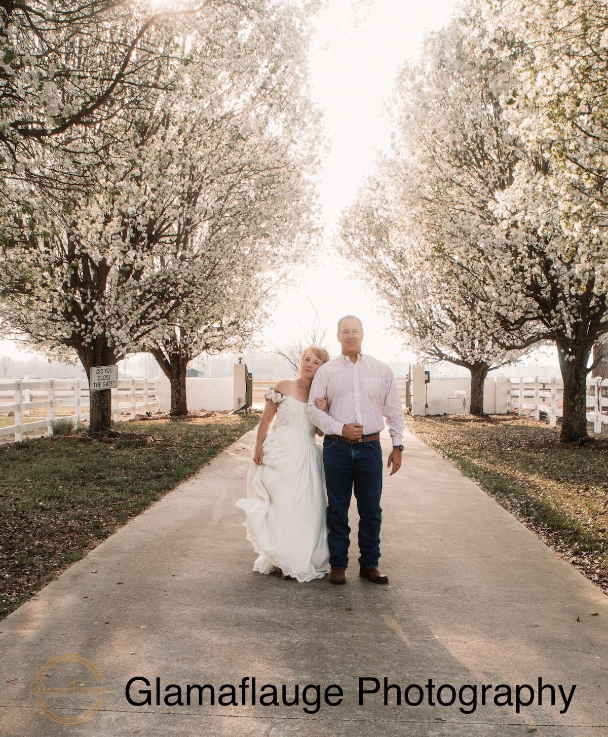 Newlyweds walking beneath blossoming trees at the Parkton Place entrance