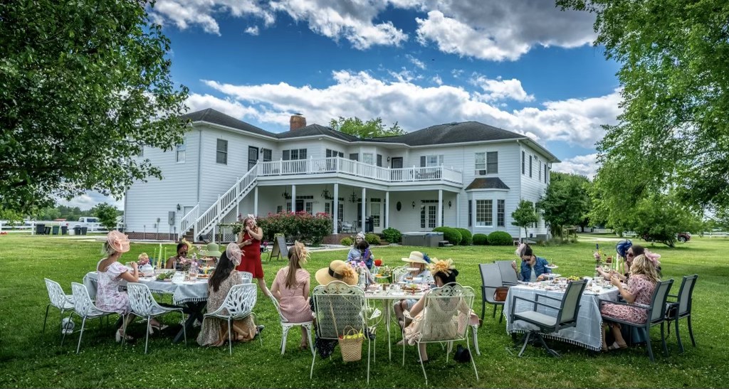 Garden tea party with guests seated at tables in front of the Parkton Place estate house