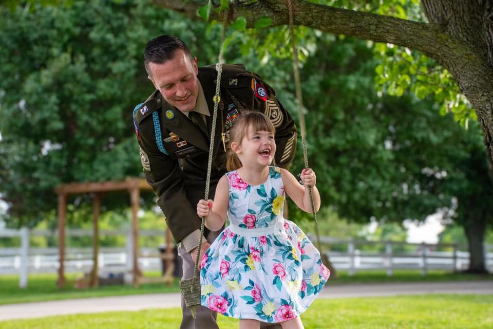 Soldier pushing his daughter on a tree swing at Parkton Place