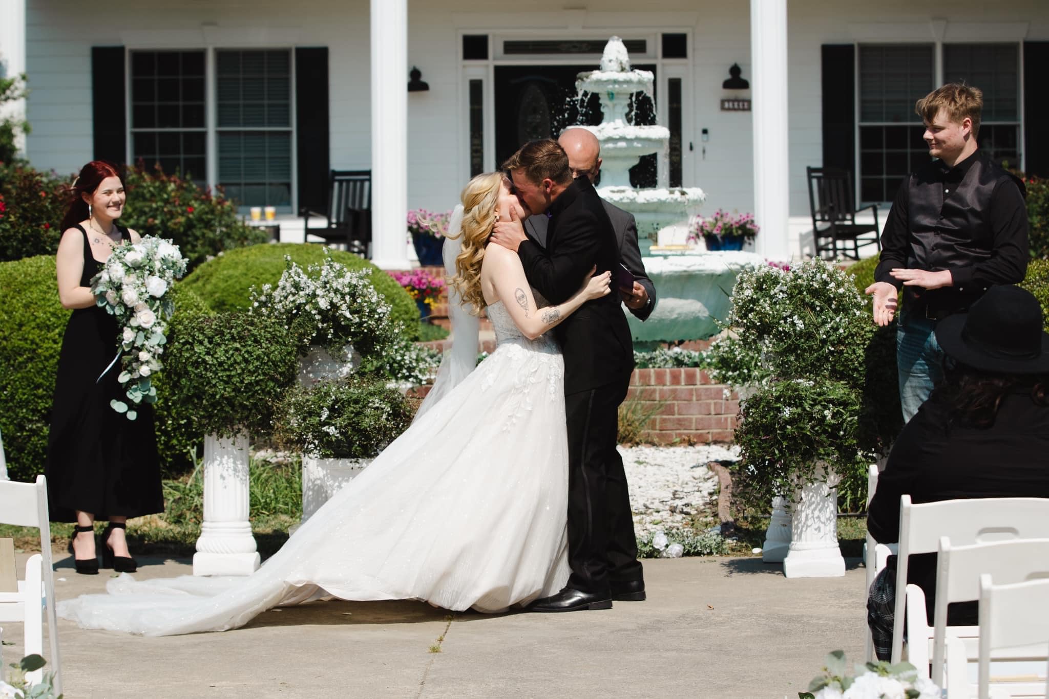 Bride and groom's first kiss in front of the fountain and estate house at Parkton Place